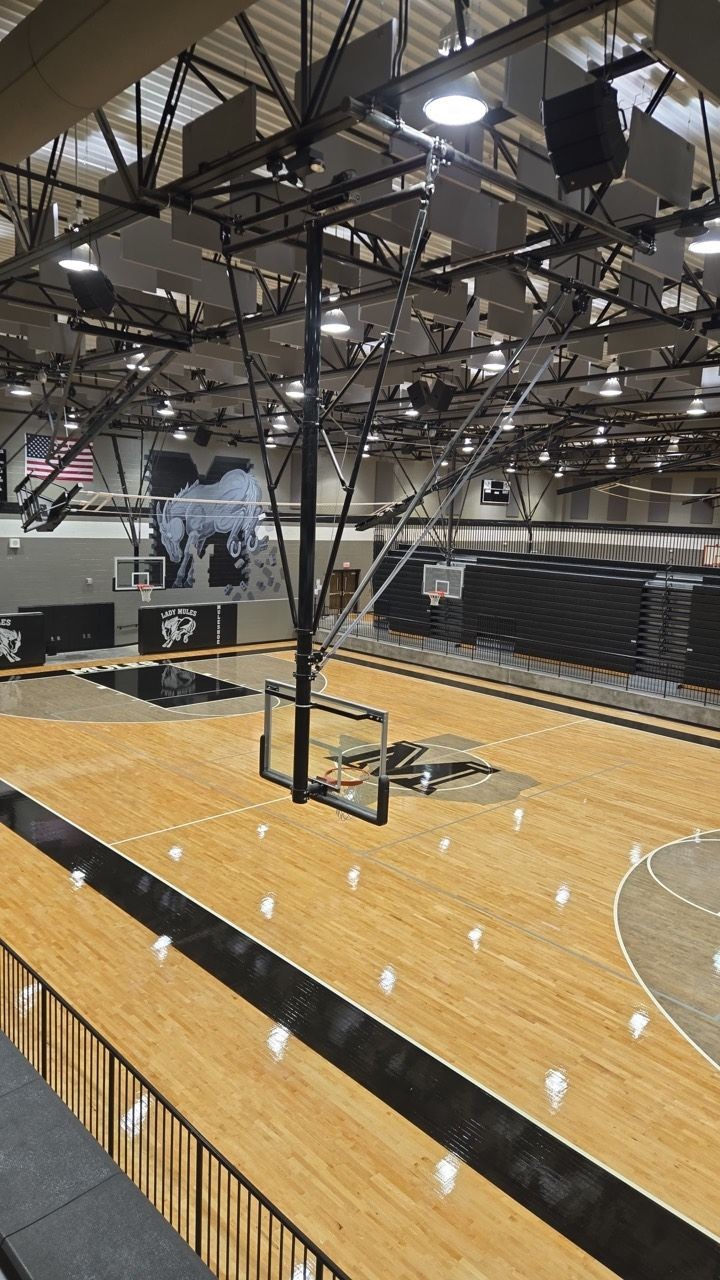 Indoor school gym with hardwood basketball courts, suspended hoops, and retractable bleachers Indoor school gym with hardwood basketball courts, suspended hoops, and retractable bleachers